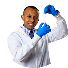 A man holding a vial with latex gloves wearing a white coat