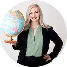 A woman smiling holding a globe of the world with her hand on her hip