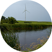 A wind turbine is in the distance near a river