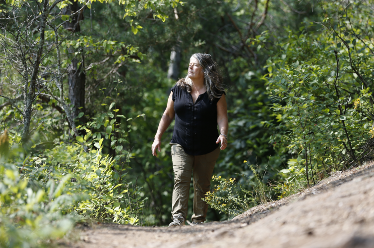 Dr. Julie Etterson walking on a wide path in a wooded area