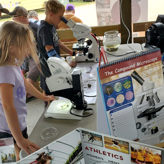 A little girl interacts with a booth at a summer science fair