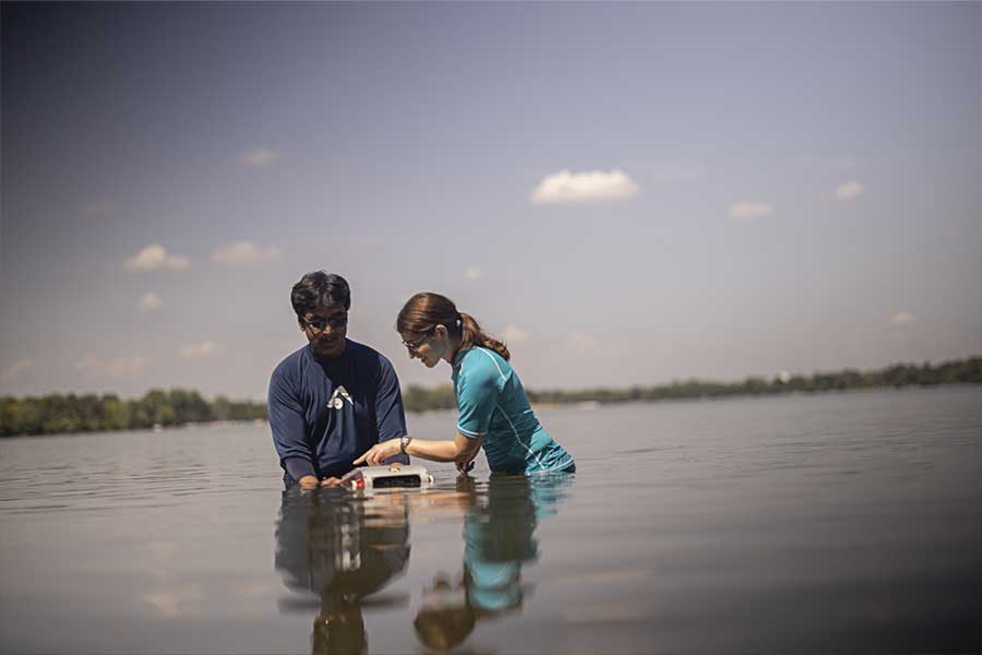Two students put a aquatic robot in a lake