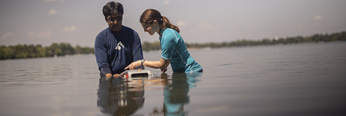 Junaed Sattar and a student place the water robot in a lake for deployment
