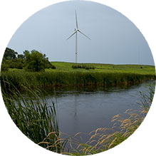 A wind turbine is in the distance near a river